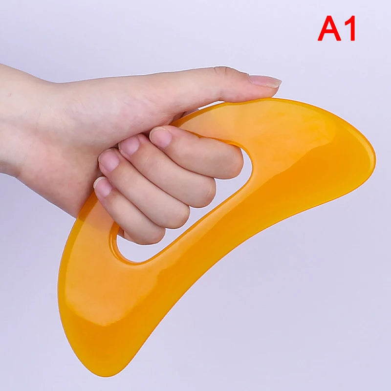 Massage Therapy Natural Stone Massagers Tools.  Picture of a yellow curve tool sizes : 18 cm X 6 cm (hole in middle to be able to grab it) held by a woman left-hand Model A1