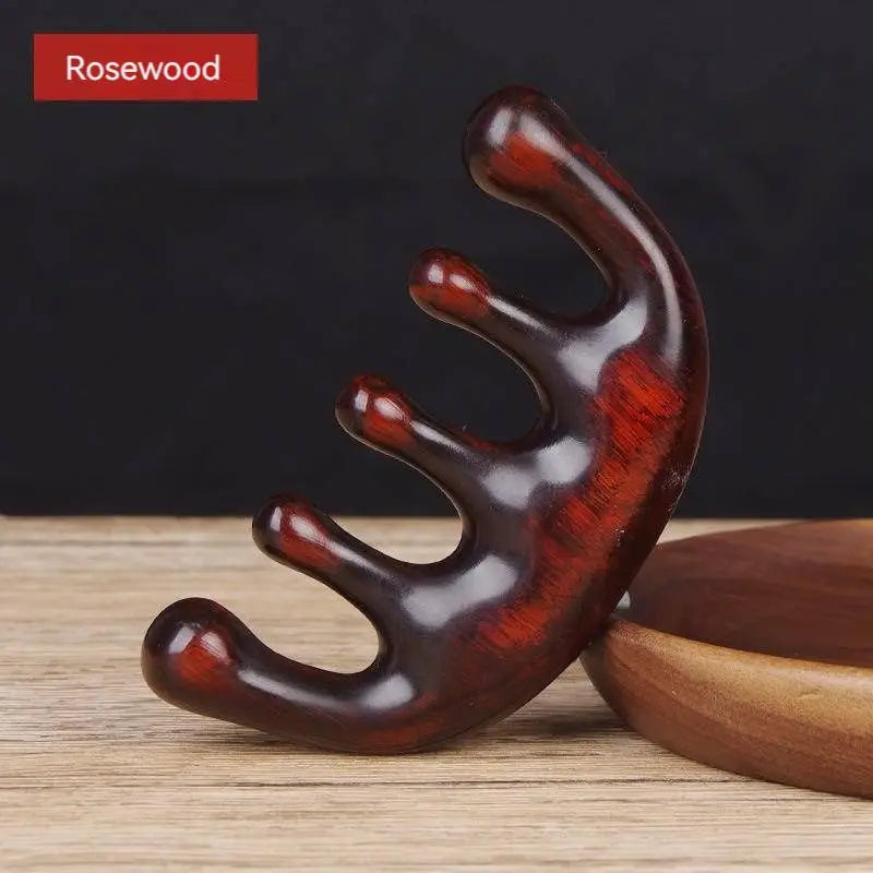 Massage Therapy Natural Wooden Massager Comb Rose-wood Colour with is 5 large wood teeth on a white wood table, leaning against a wooden circle