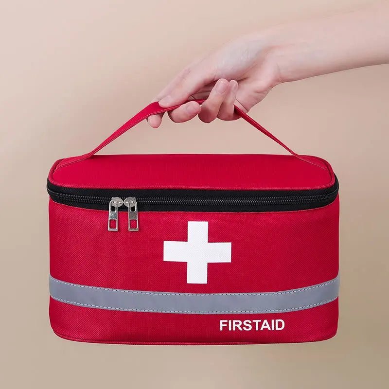 Medical Supplies Equipment One First Aid Medicine Storage red bag with the white cross in front and First Aid name on it. The picture show the large size with the strap being handle by a woman hand.