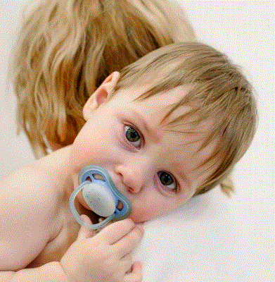 Free Picture of a baby with a pacifier on his mother shoulder - Blog: Thumb Sucking, Pacifiers, and Your Child’s Dental Health.