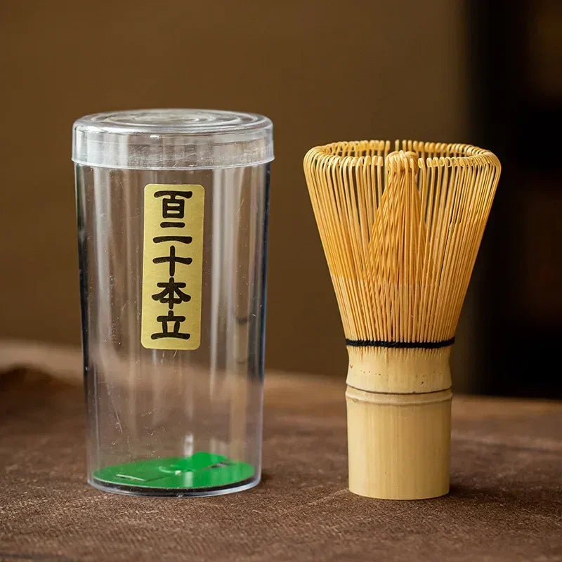 Massage Therapy Accessories Japanese Geisha Tea Set Matcha Whisk Picture of the whip and its plastic container with Japanese inscriptions placed on a woven bamboo doily on a wood table