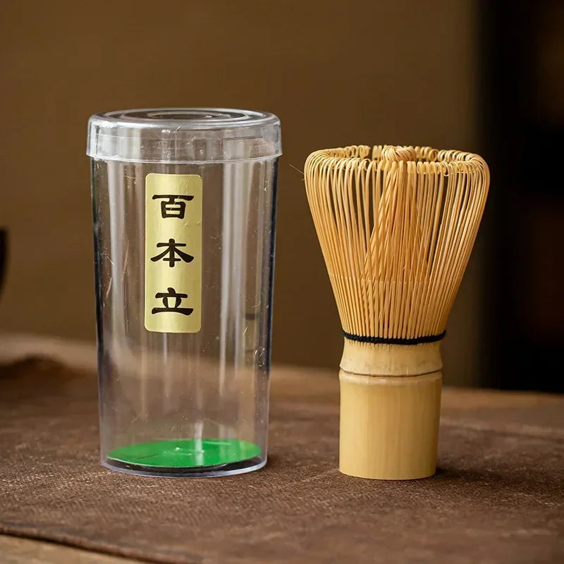 Massage Therapy Accessories Japanese Geisha Tea Set Matcha Whisk Picture of the whip and its plastic container with Japanese inscriptions placed on a woven bamboo doily on a wood table